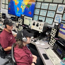 a pair of ham radio operators at a large station console