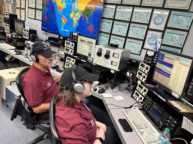 a pair of ham radio operators at a large station console