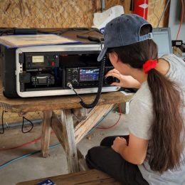 woman tuning a portable ham radio station at park bench