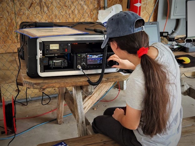 woman tuning a portable ham radio station at park bench