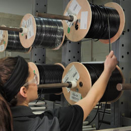 woman unwinding coaxial cable from large spool