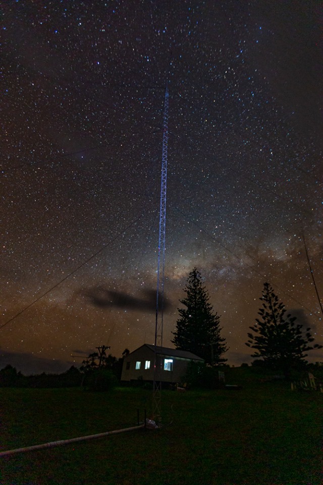 dark photo of ham radio shack & antenna against starry night