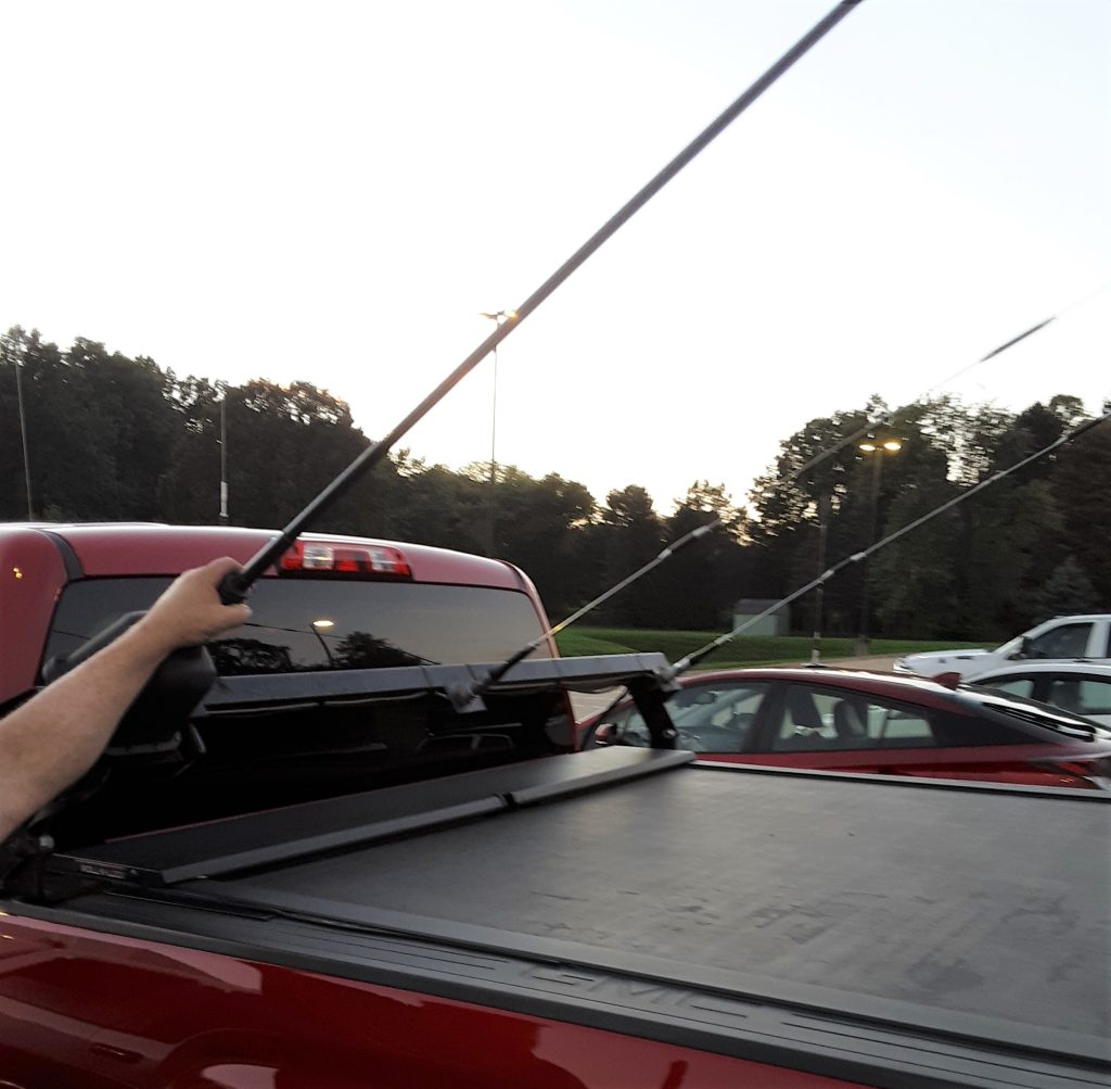 man tilting large mobile ham radio antennas onto truck bed