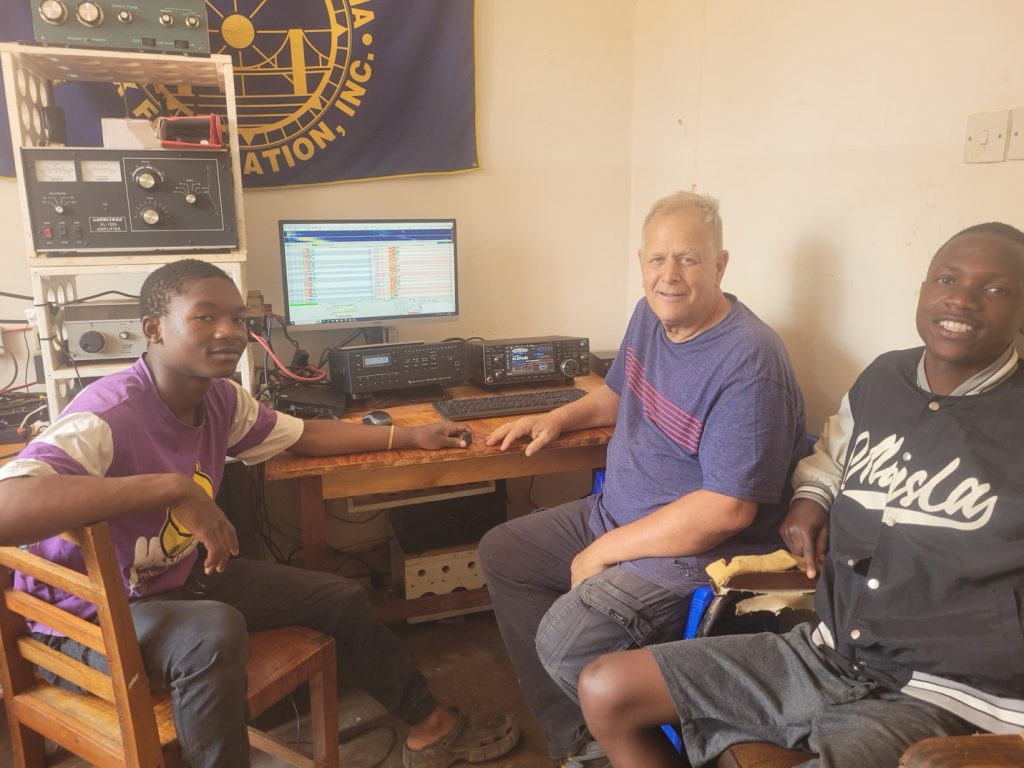 Men sitting near amateur radio station equipment