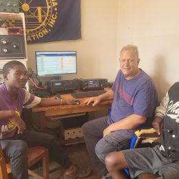 Men sitting near amateur radio station equipment