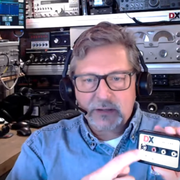 man holding a ham radio module in a ham shack