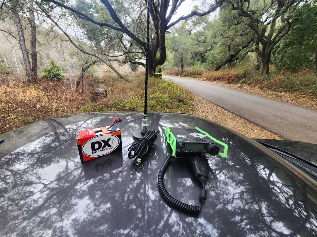 Ham radio and antenna resting on the roof of a car