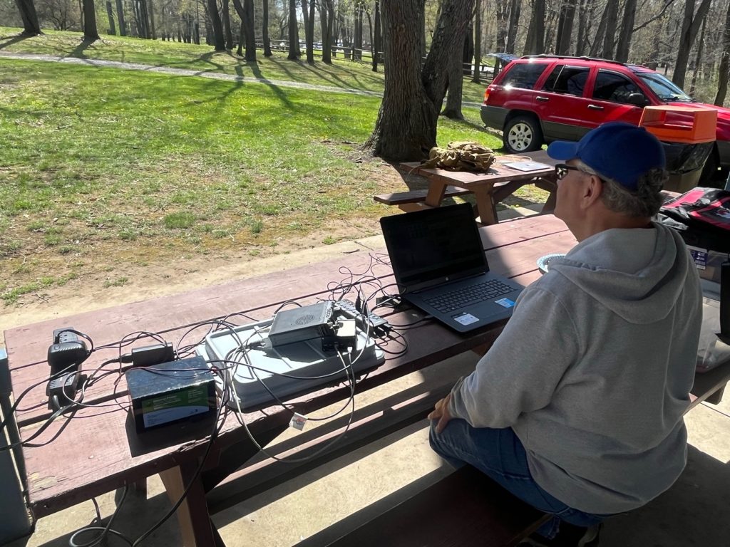 man sitting at an outdoor portable ham station