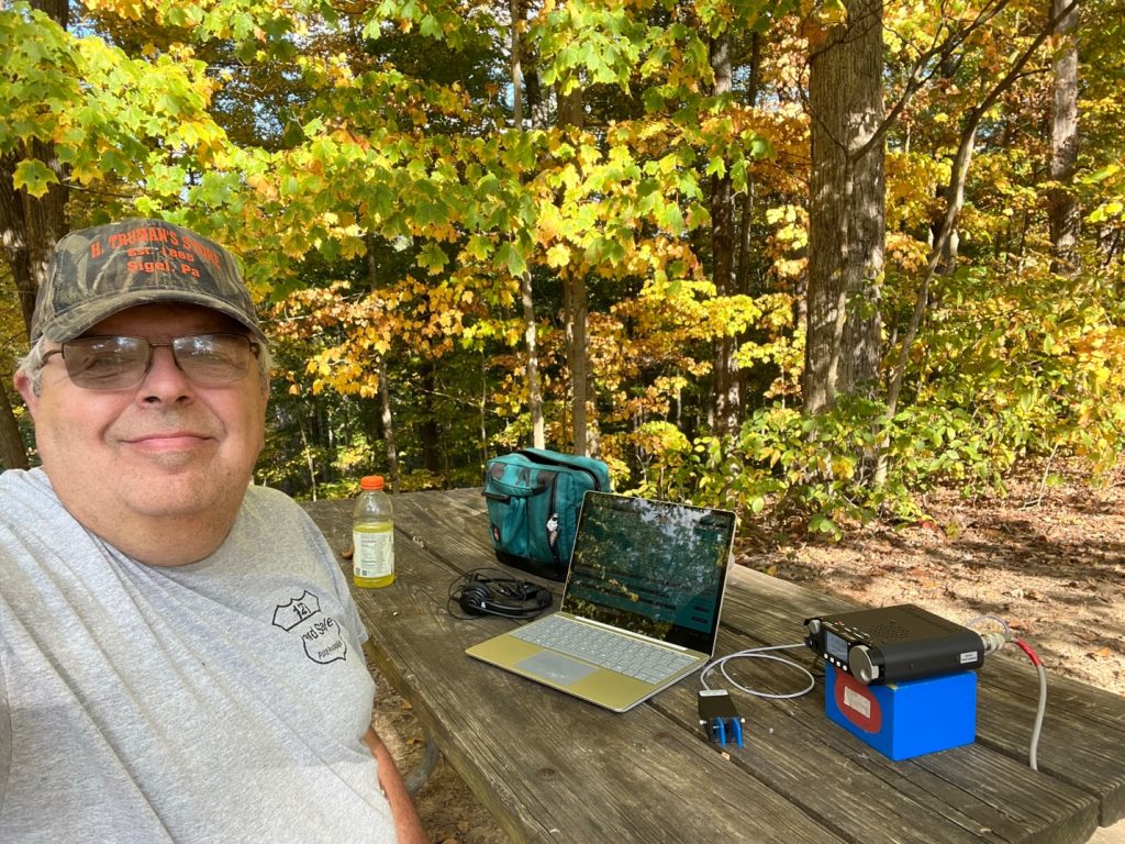 man at picnic table with a small ham radio